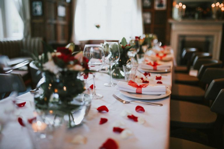 Wedding table setting decorated with fresh flowers and silverware. Concept of fine dining, catering and exclusive private hire of an event space. Banquet table set up for a wedding reception or dinner.