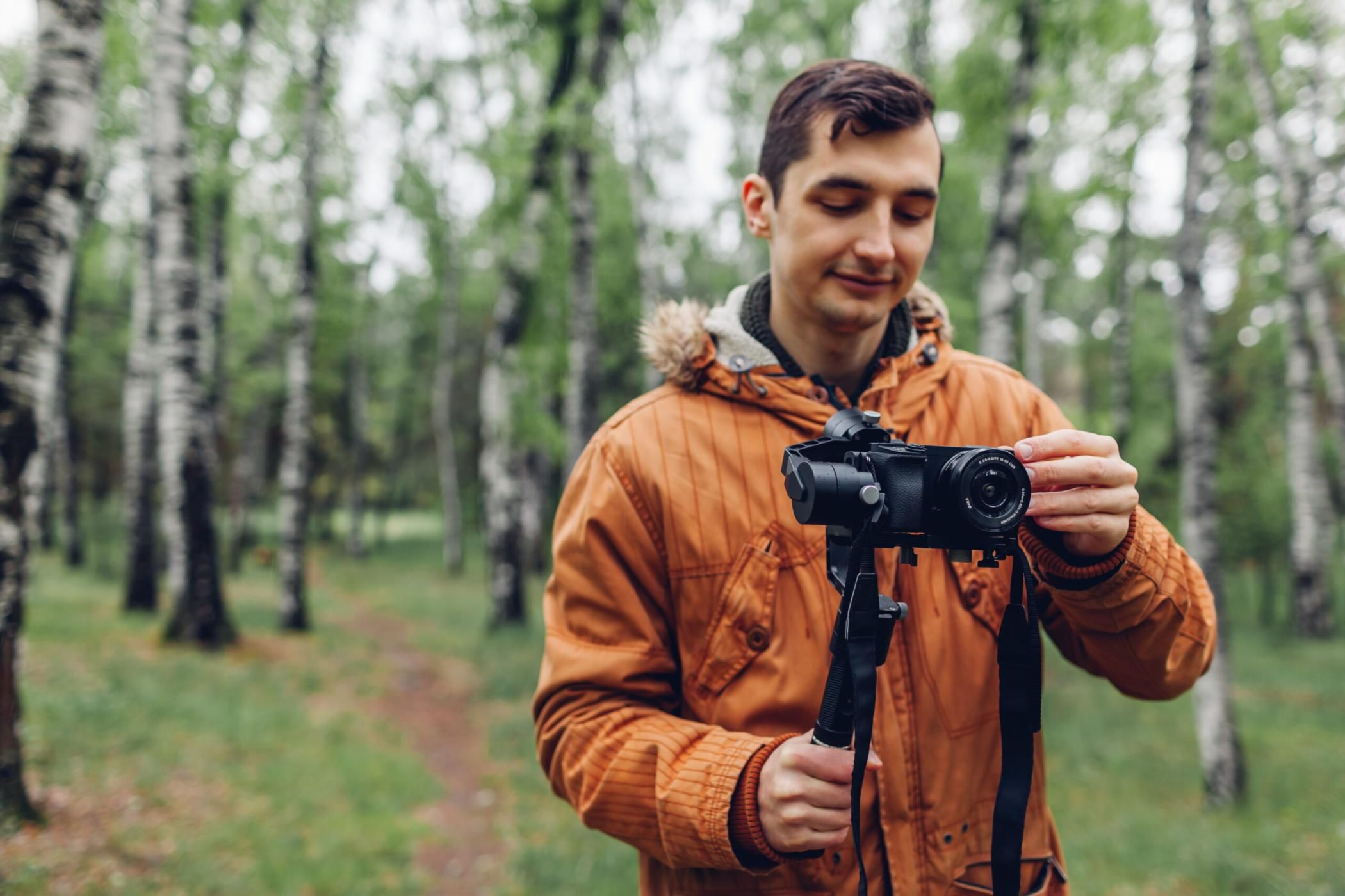 Videographer filming spring forest. Man using steadicam and camera to make footage. Video shoot. Digital devices for video shoot
